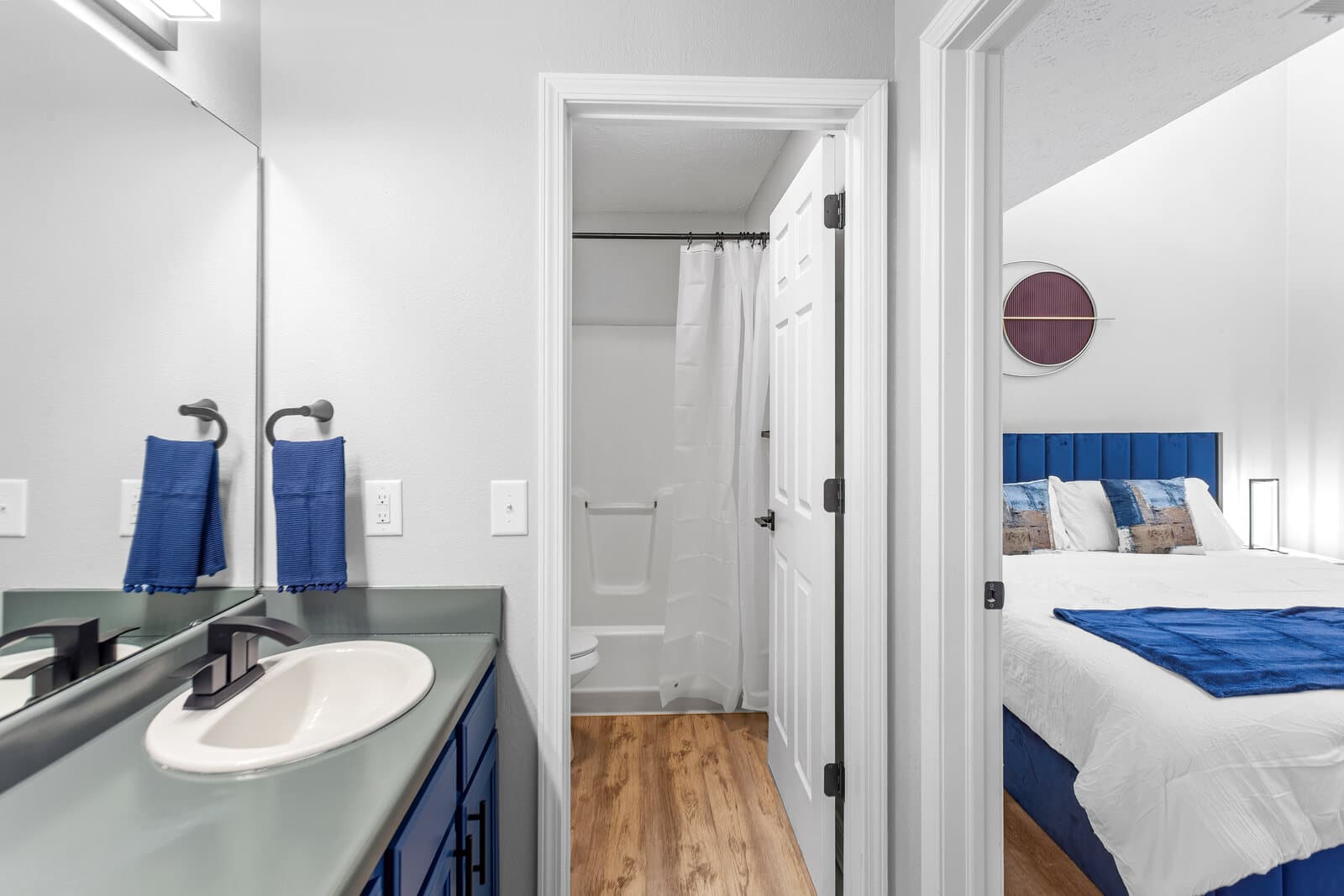 Bathroom vanity with blue cabinetry and a bedroom visible beyond