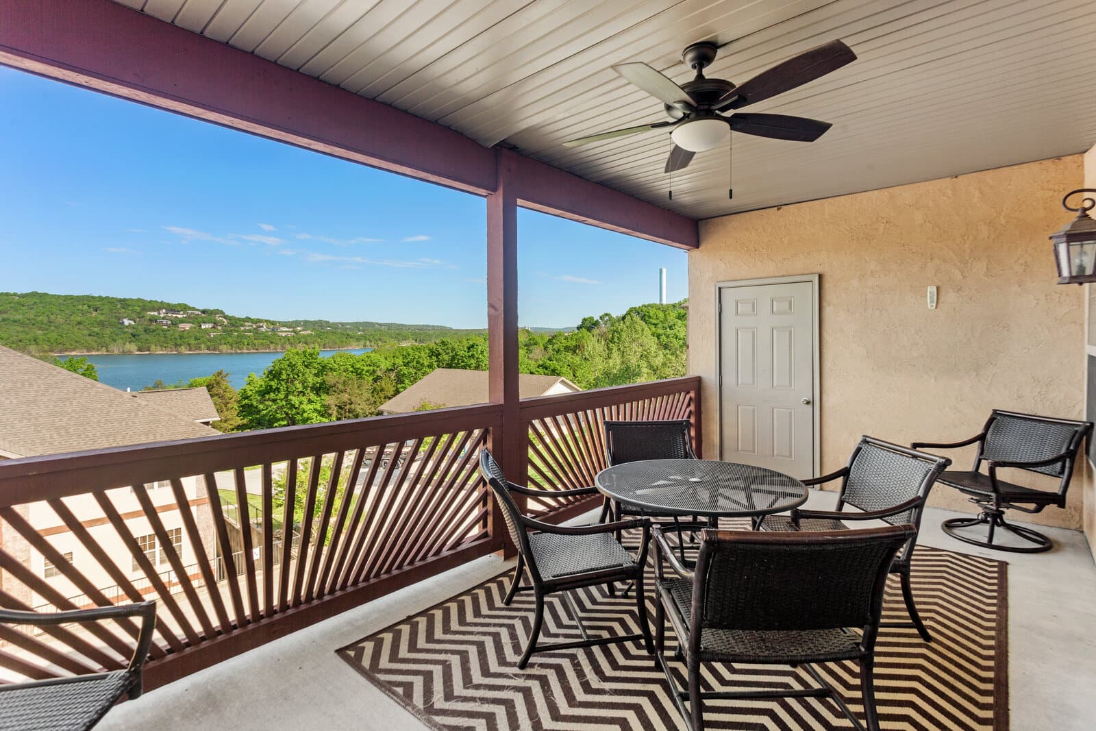 Covered balcony with patio seating and a hillside lake view