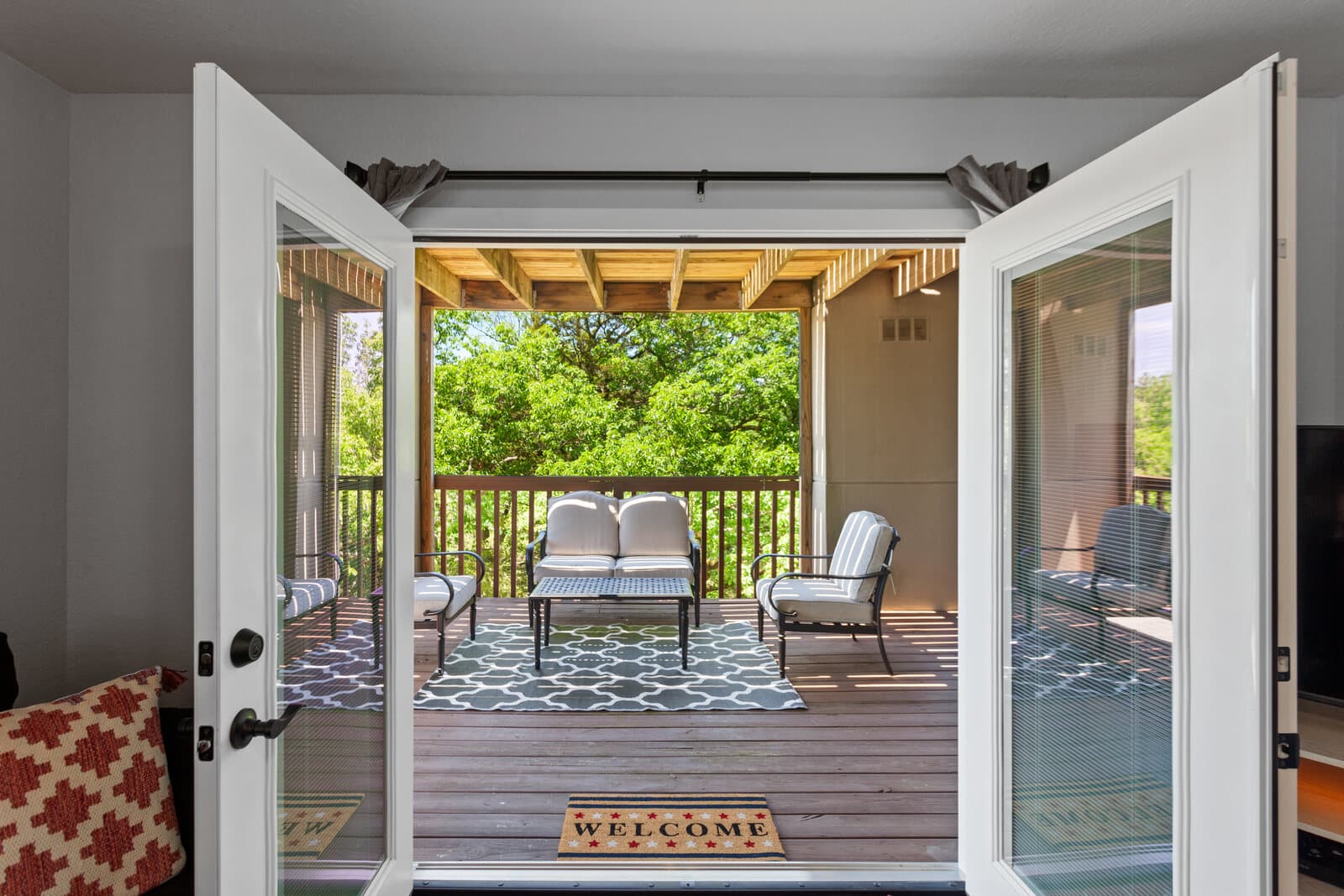 Covered back porch with patio seating, seen through open French doors