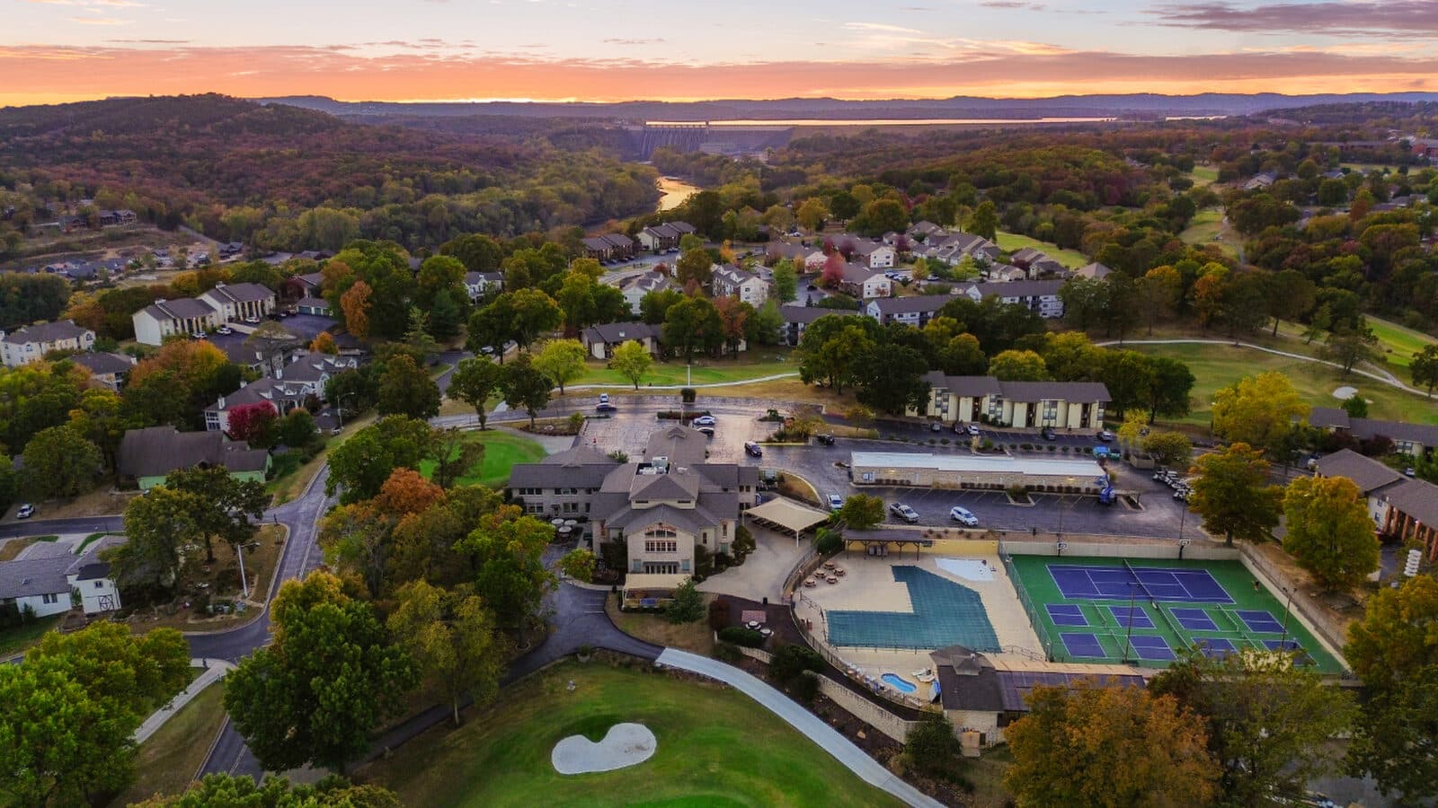 Dusk aerial of a hilltop community with pools and courts