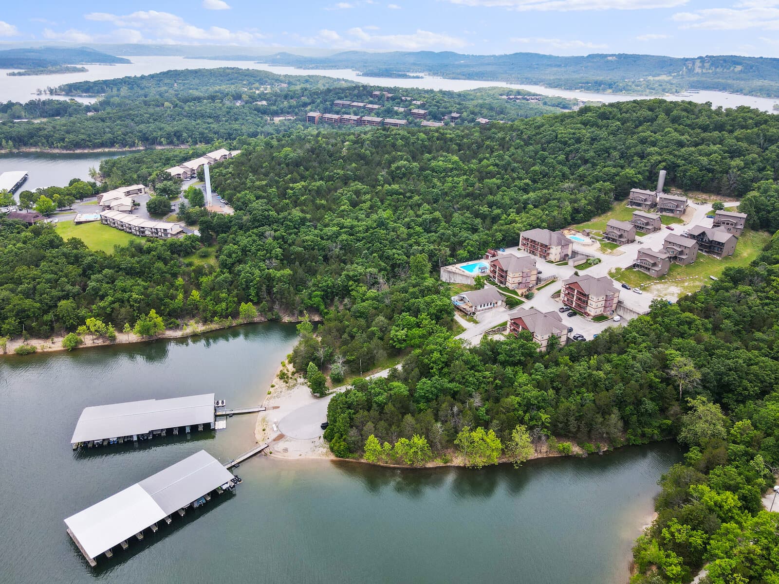 Aerial of a lakeside condo resort with covered boat docks and a pool