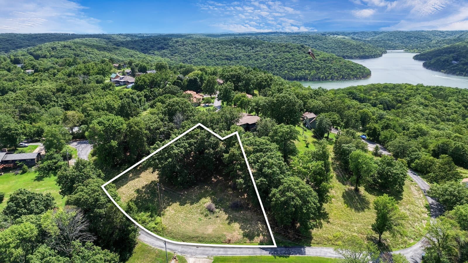 Aerial of a marked residential lot with lake and wooded hills beyond